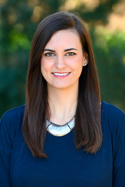 A professional headshot of Dr. Amanda Pascale with long brown hair and a green blurred background 