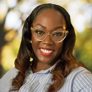 Headshot of Artrice Johnson smiling with greenery in the background.