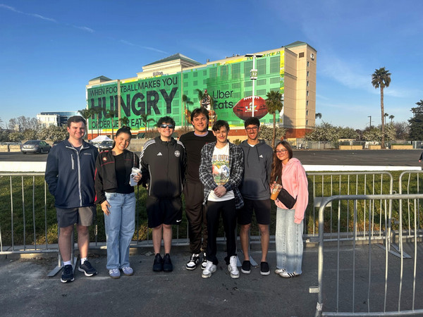 Group photo of sport management students in front of super bowl advertisement on building