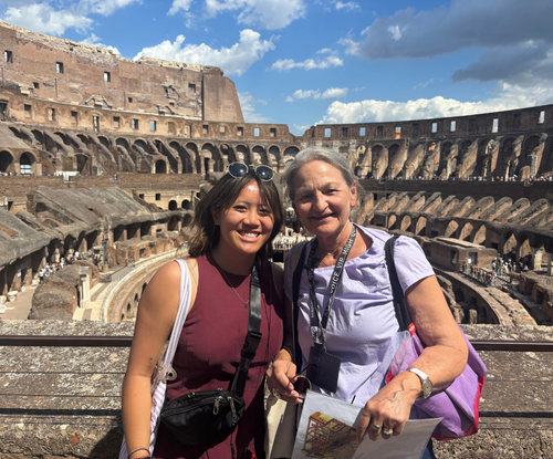 Two women smiling inside the Colosseum on a sunny day in Rome