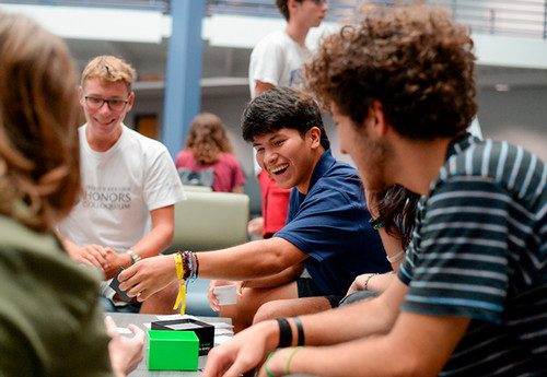 Students smile and laugh while playing cards together.