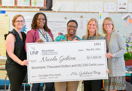 Gladys Prior Award winner poses with administrative team, holding giant check.