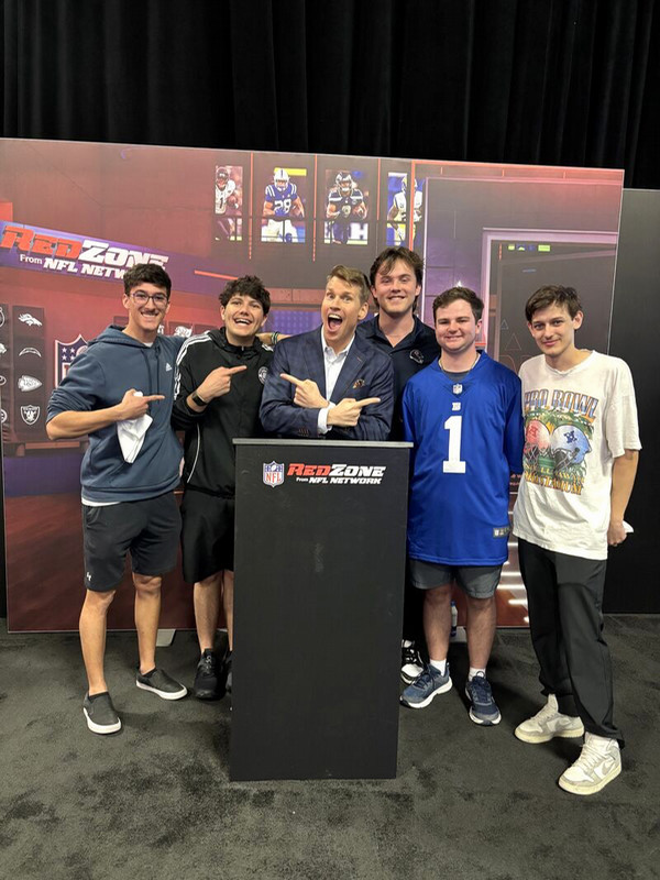 Sport Management students smiling behind Red Zone podium