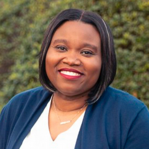 Headshot of Sheryl Patterson-Coulibaly smiling outdoors with greenery in the background.