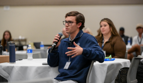 UNF student in the audience speaking into a microphone at the Silverfield Coaching Symposium