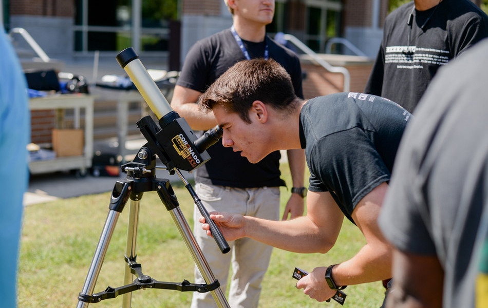 Student looking through a telescope into the sky