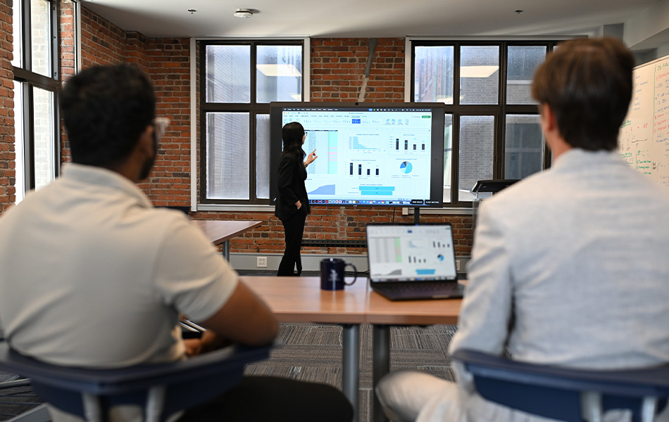 UNF student presenting a business analytics spreadsheet at a work environment