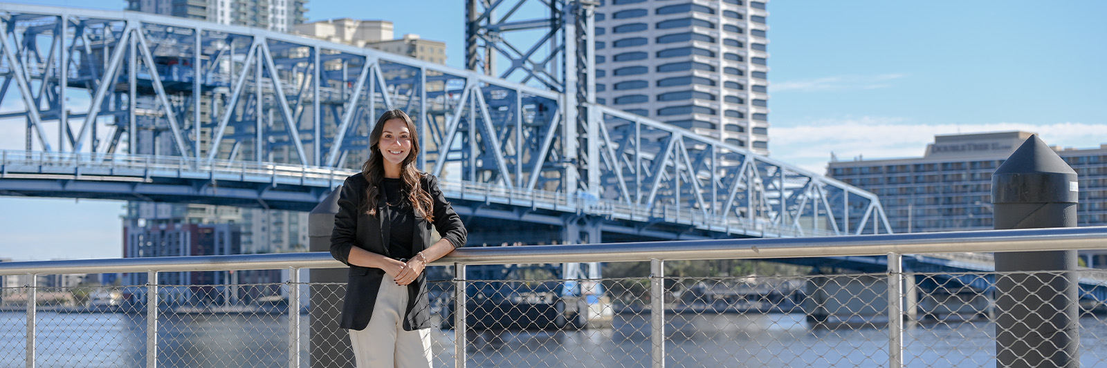 Student posing in front of Jacksonville Main Street Bridge