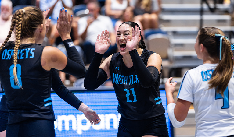 UNF women's volleyball players celebrate together