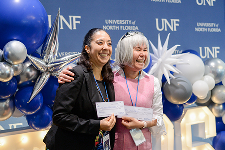 two employees holding up certficates at an event