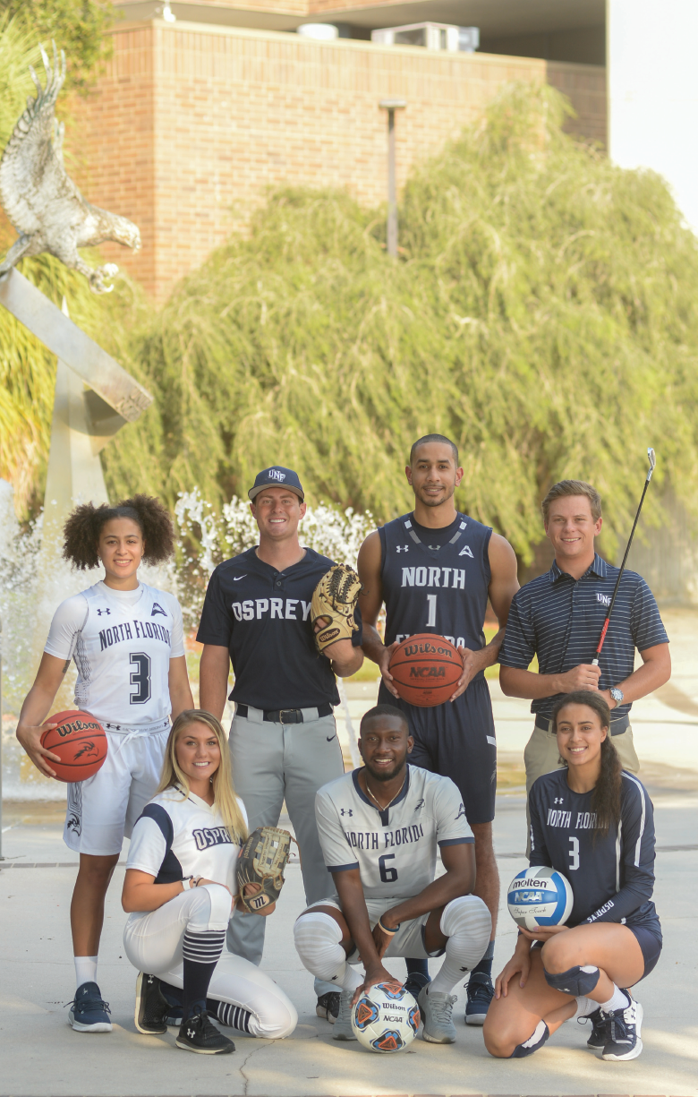 Seven UNF Osprey athletes standing together in their uniforms and smiling