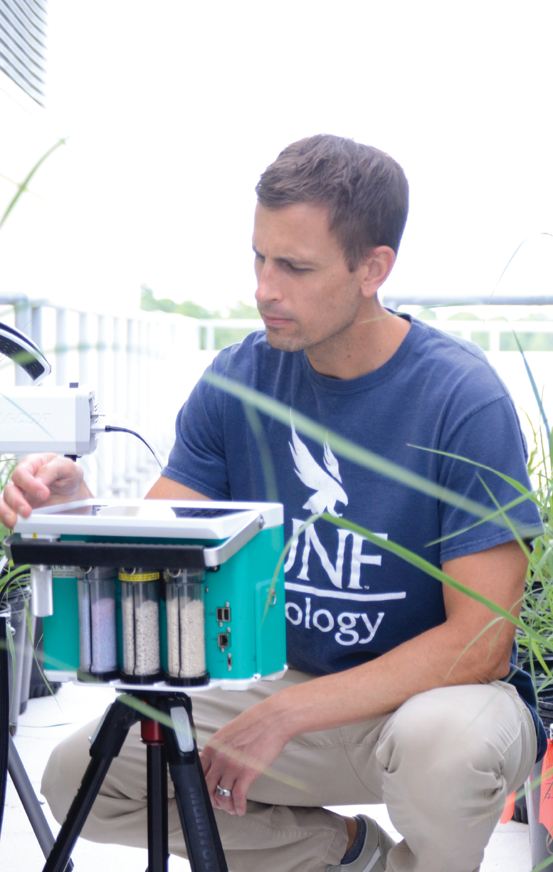 UNF Professor outside in a UNF t-shirt with lab equipment