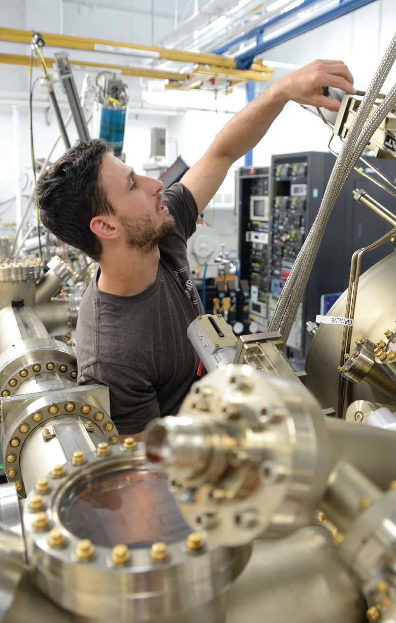 Male student in a lab surrounded by engineering equipment and machines