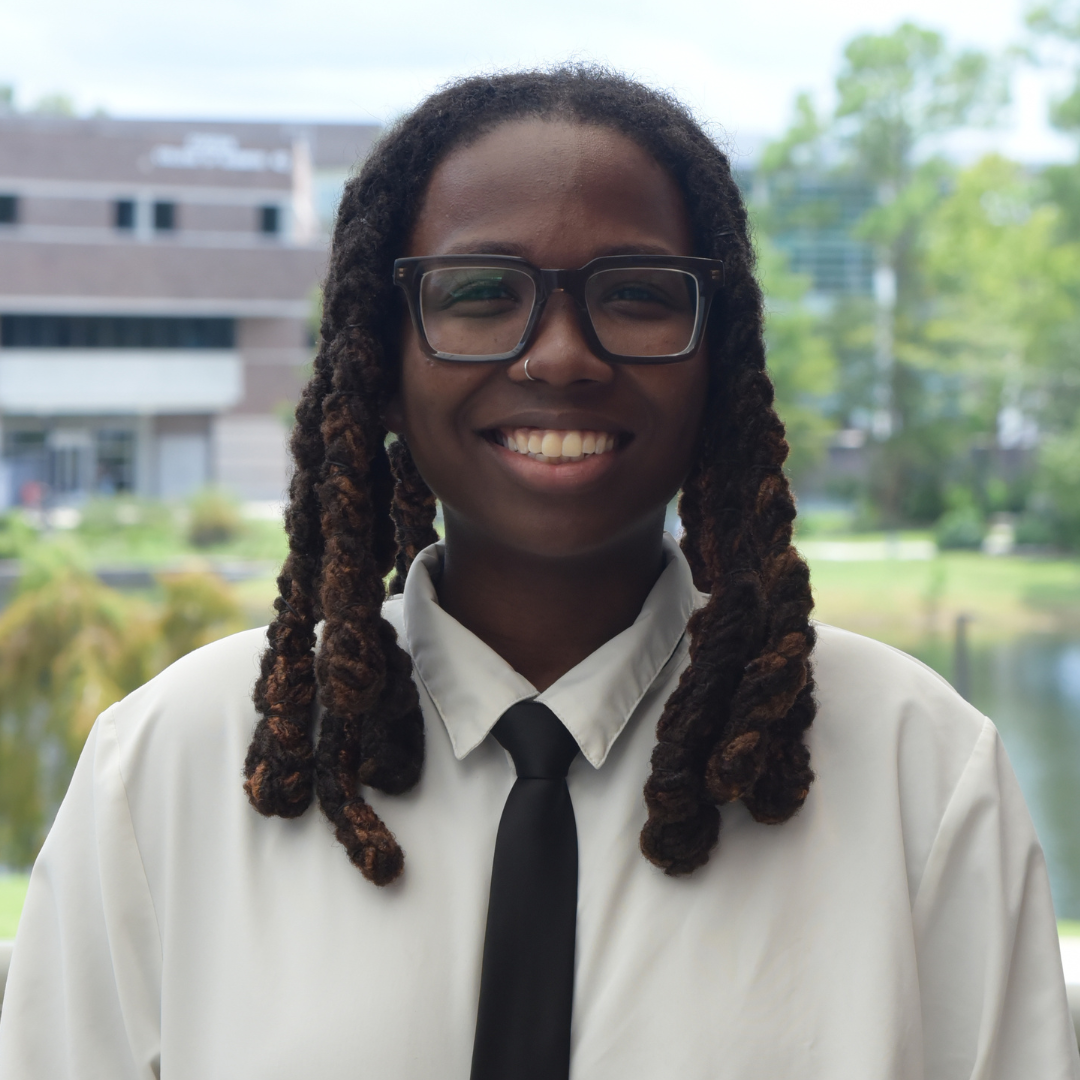 Ali is standing outside wearing a white shirt and black tie.