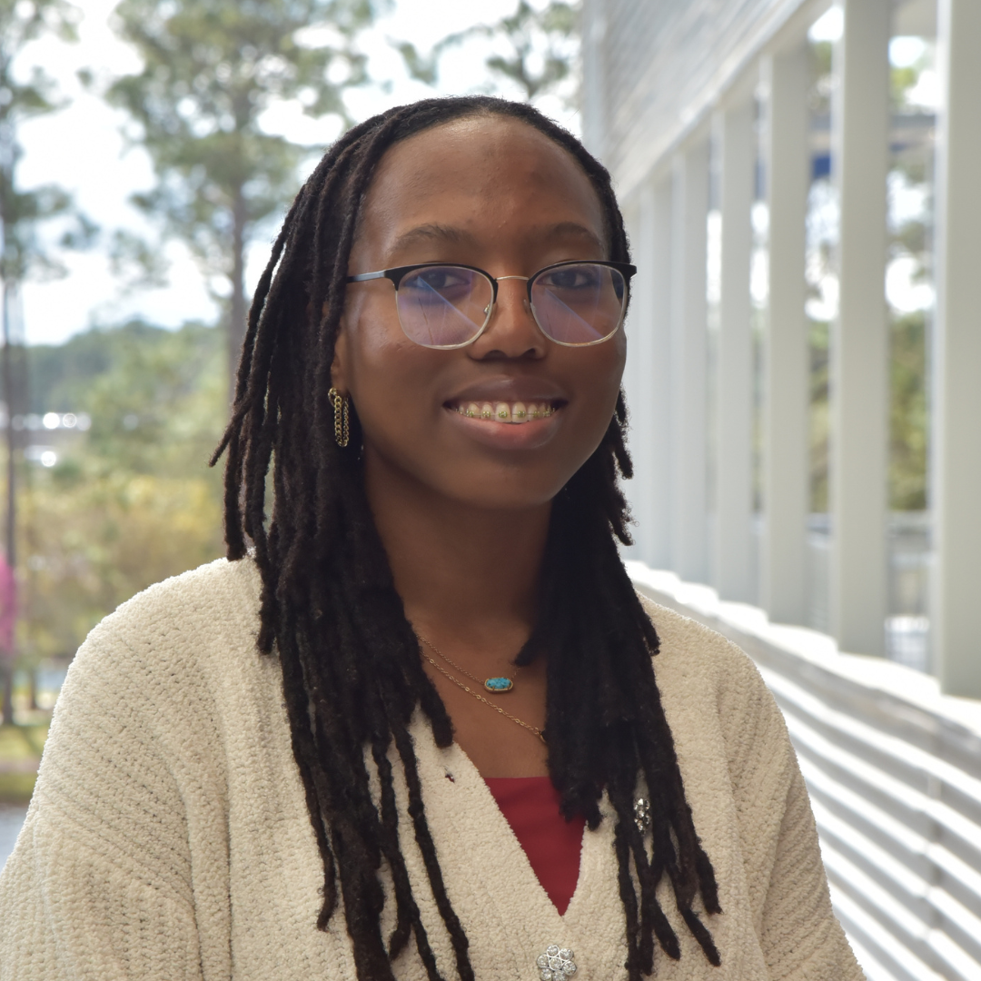 Ana is wearing glasses and standing outside