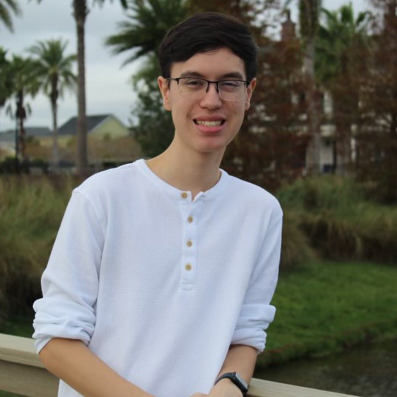 Carter in a white shirt leaning against a bridge