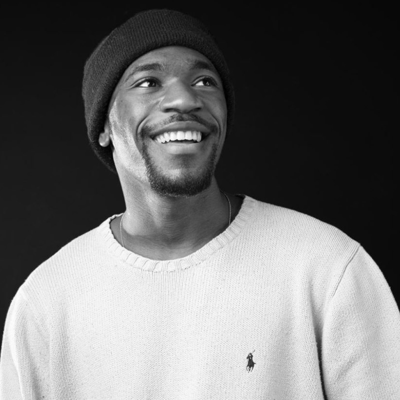 A black and white photo of Darvin in a white sweater and dark beanie