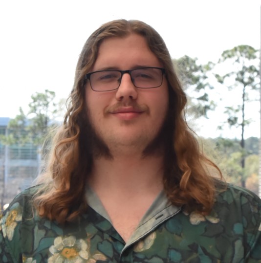 Jack has long blond hair and he is wearing a Hawaiian shirt.