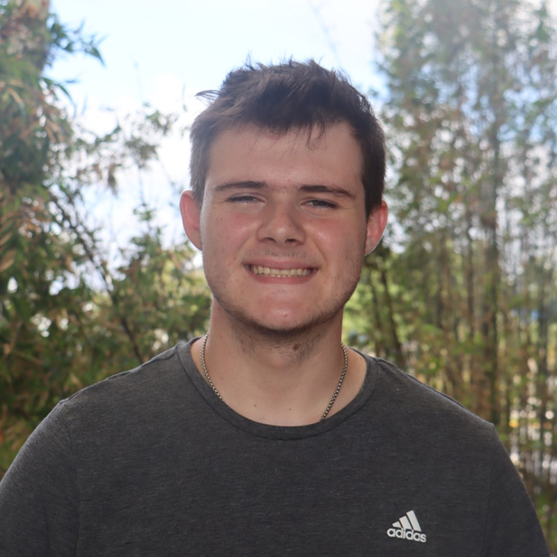 Jacob in a grey shirt standing in front of bamboo