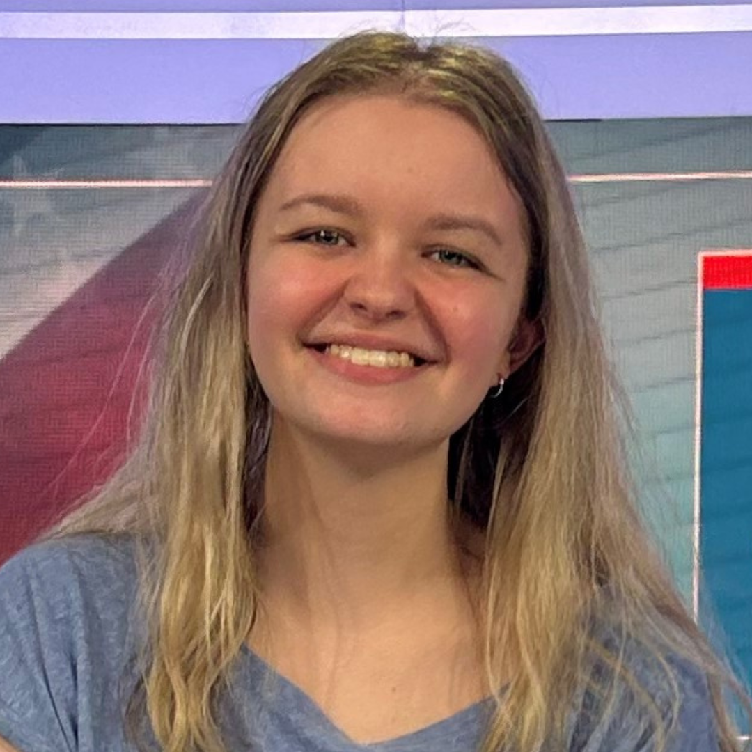 Kaylee has blond hair and is sitting on a TV set