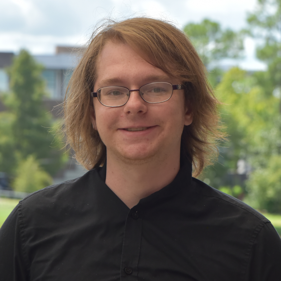 Matthew is wearing a black shirt and glasses.