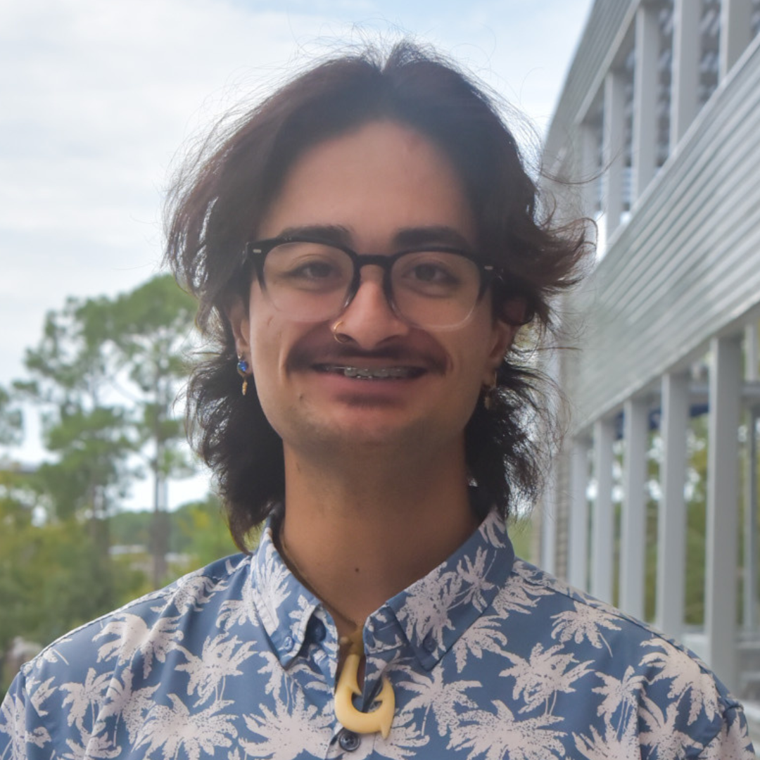 Maui is wearing glasses and a blue and white Hawaiian shirt