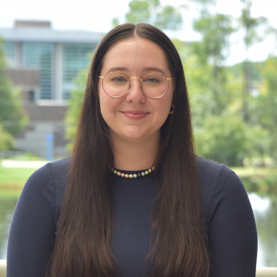 Mindy is wearing a blue shirt and standing outside