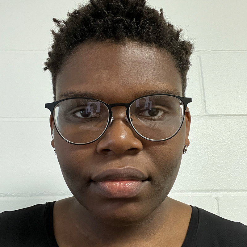 Rachel is wearing black glasses and a black t-shirt