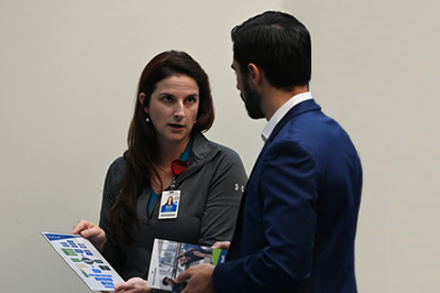 student talking with business women who is holding up a flowchart