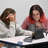 two students studying together on a laptop