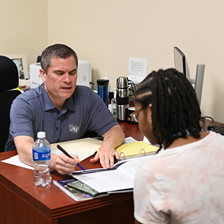 advisor working with a student at a desk