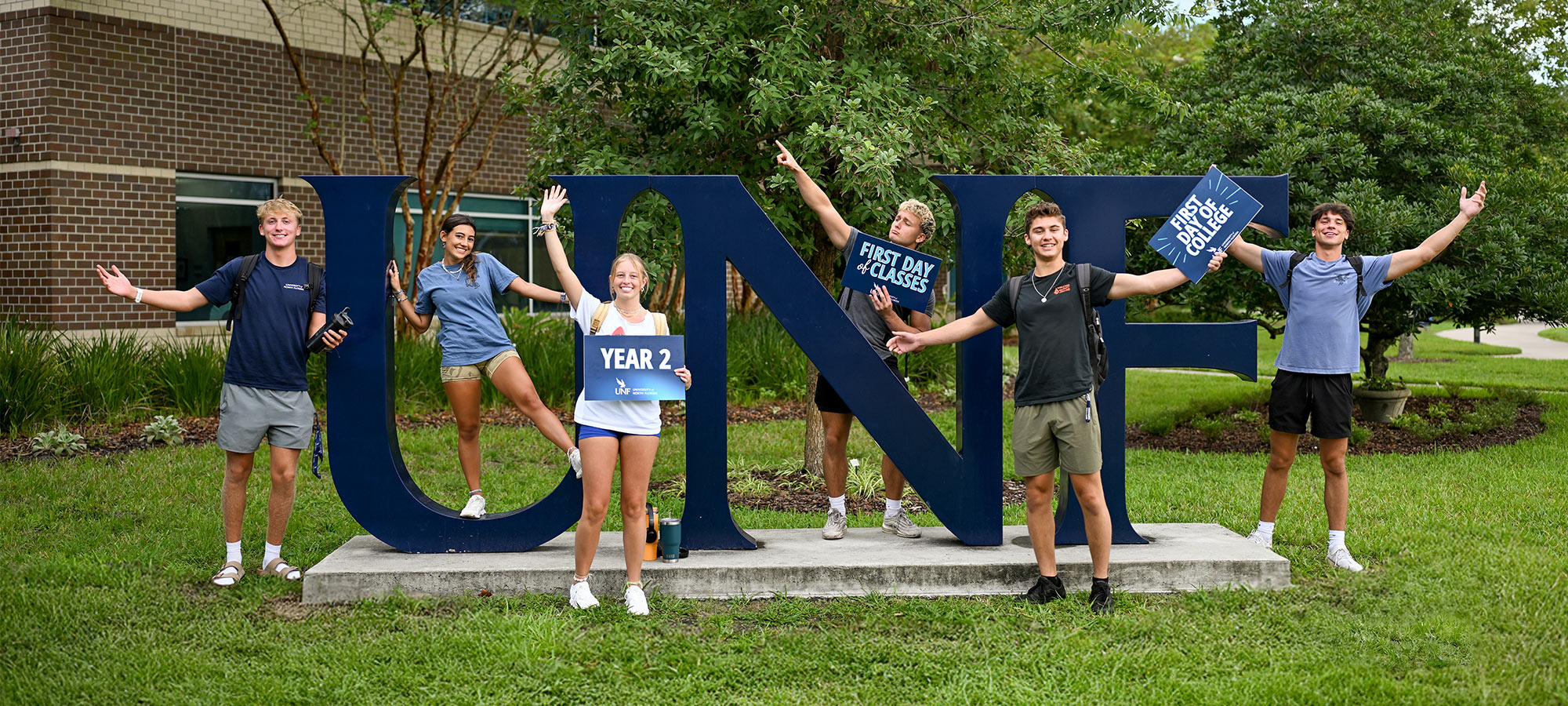 Students standing around the UNF letters and holding signs about starting classes in Year 2