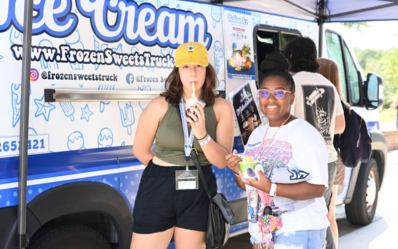 two students enjoying treats from a food truck