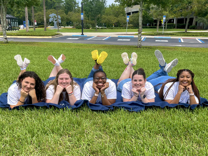 five students posing on a blanket