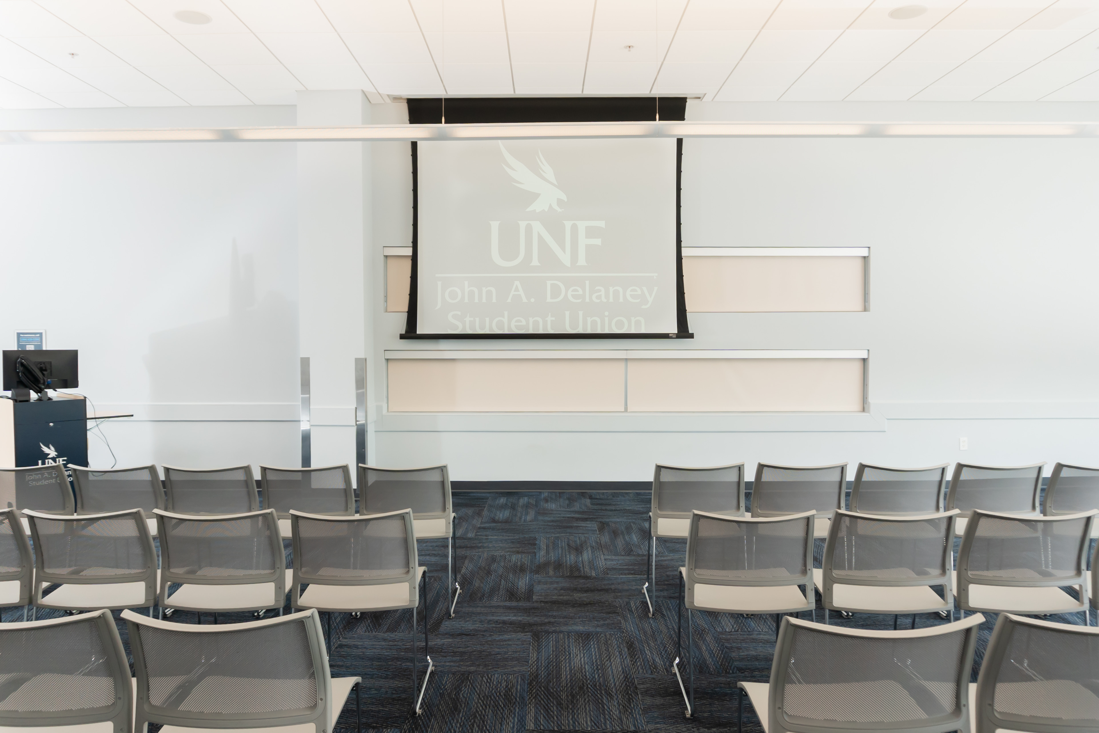 room with rows of chairs, projector screen, computer