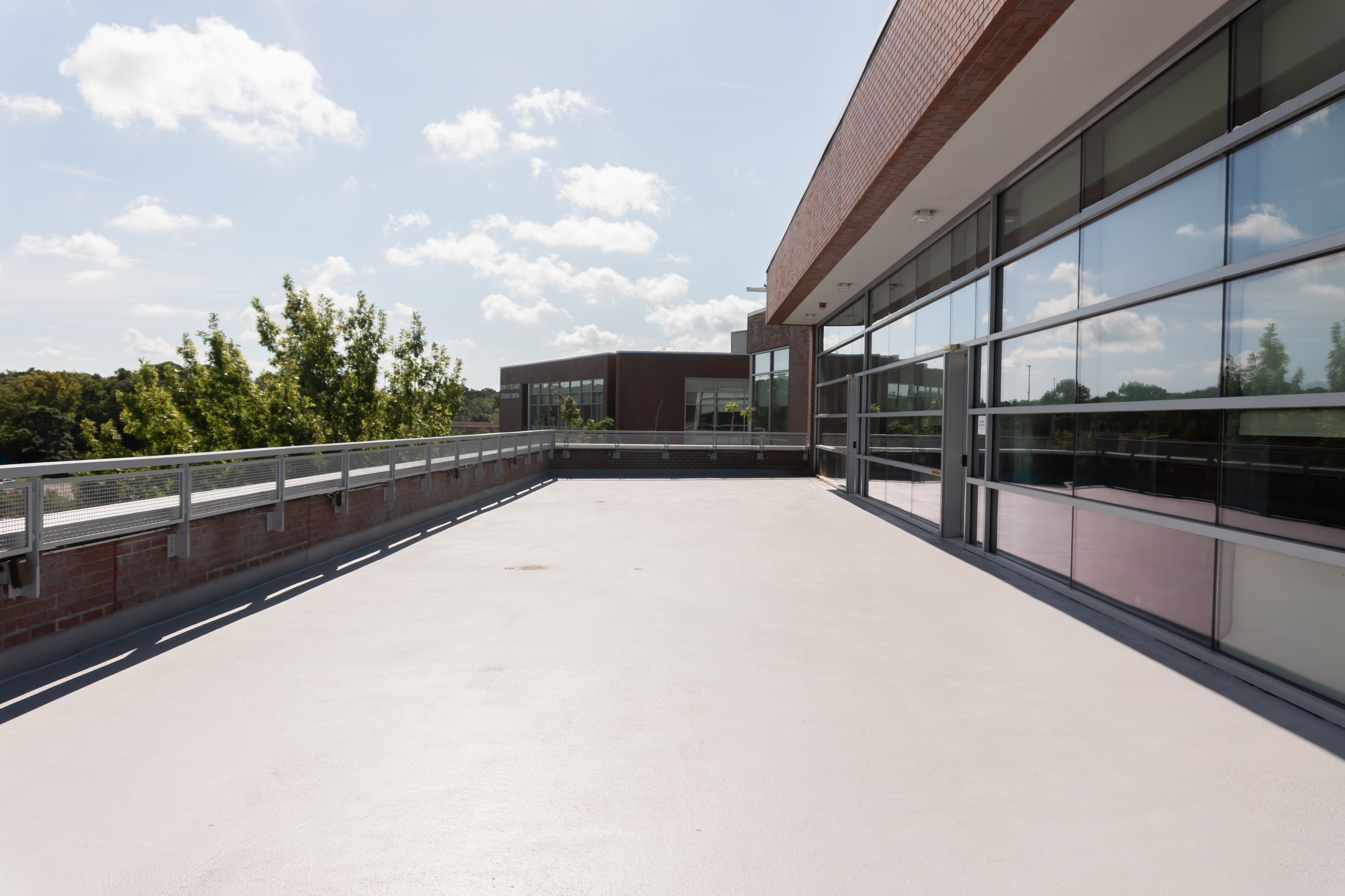 outdoor patio with 2 sides low brick wall and wall of windows