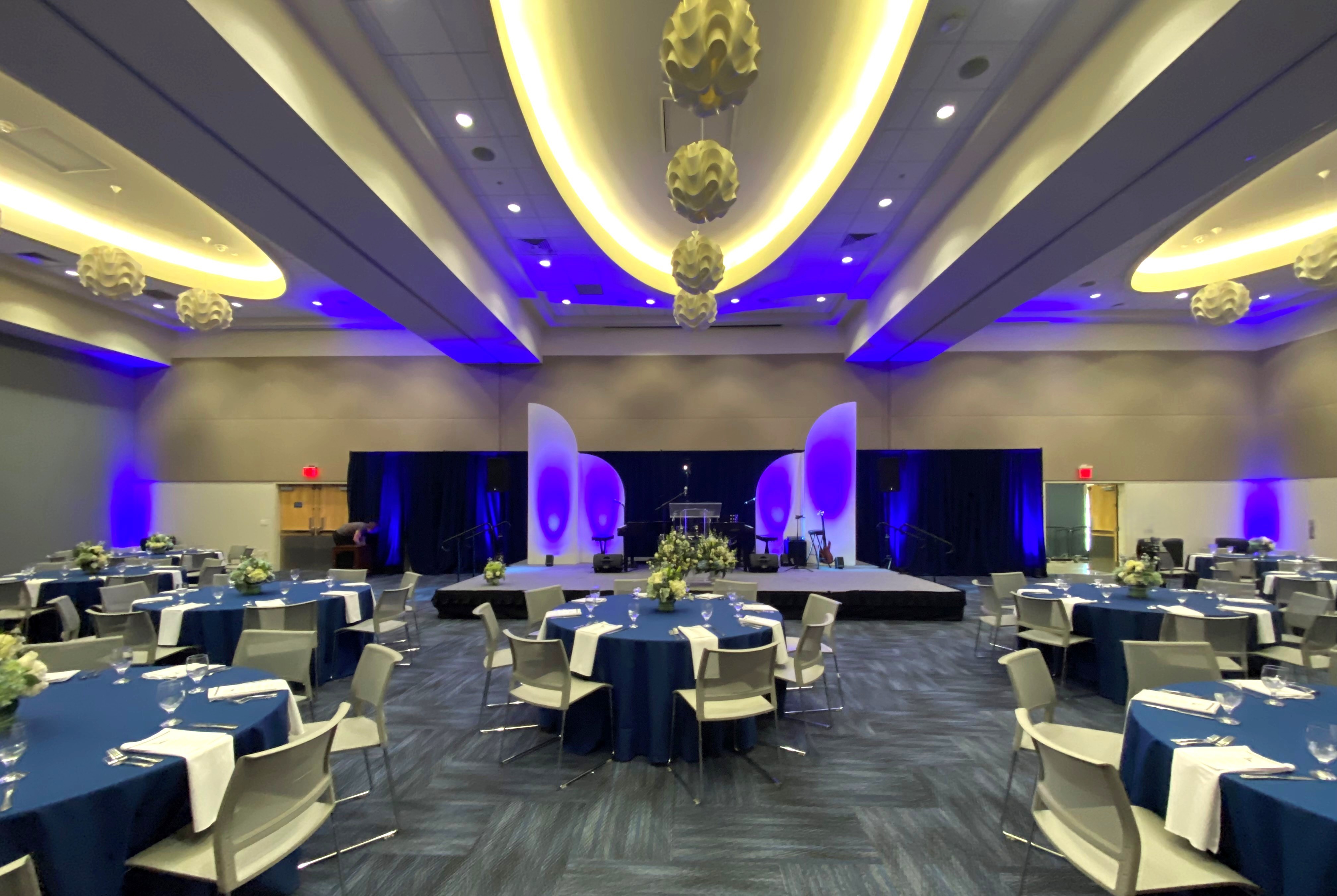 stage with backdrop and banquet tables with navy linens