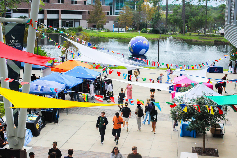 Vendor tents with people walking through and flag banners above