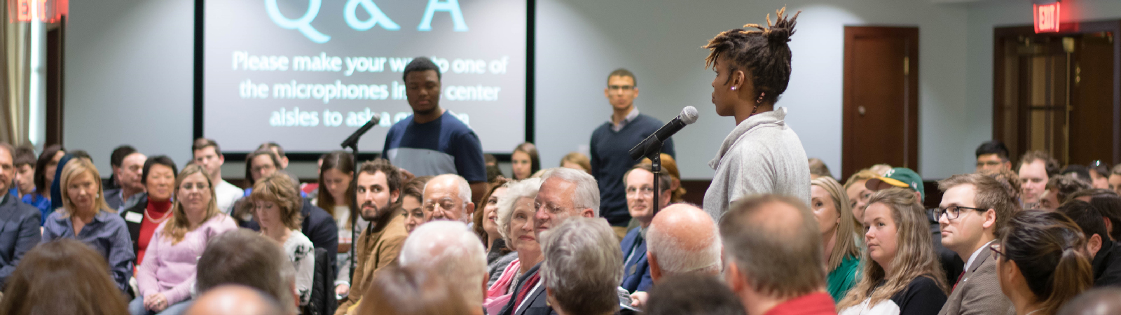 Three students standing at microphones in a crowd during a Leadership Speakers Series event