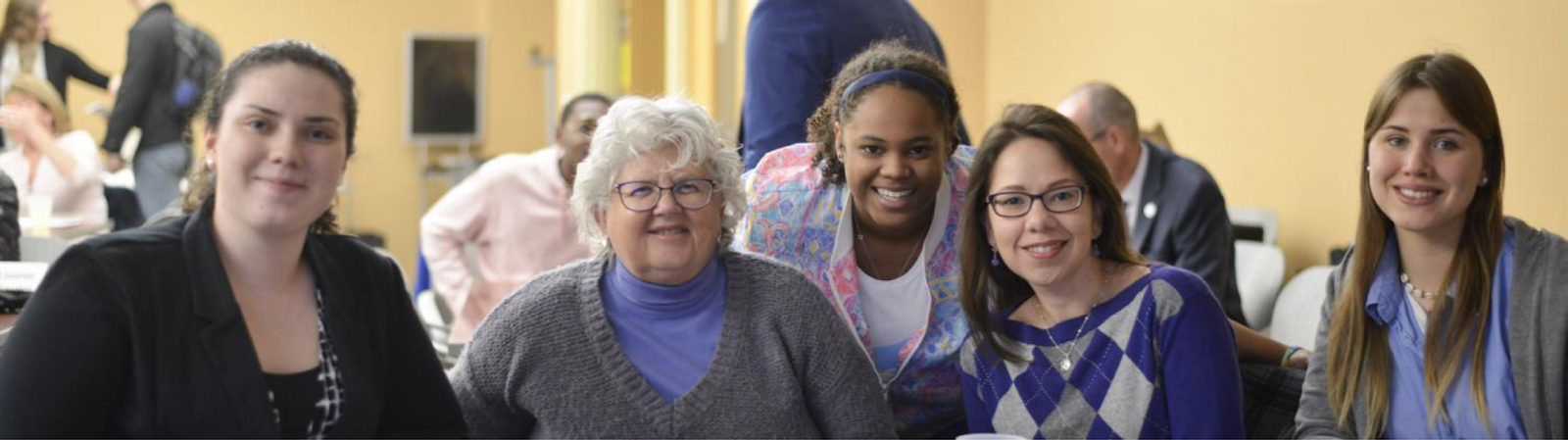 Female students and staff looking at the camera and smiling during the TLI Mentor Orientation event