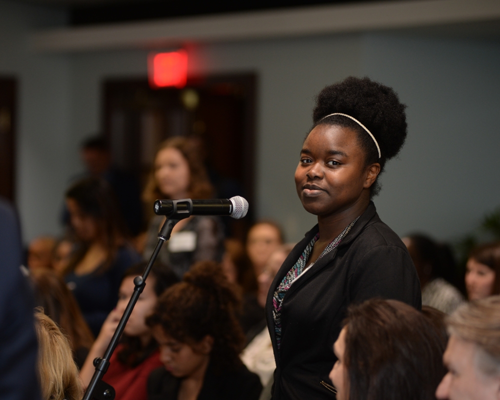 Student looking at the camera while standing at a microphone in the crowd during a Leadership Speakers Series event