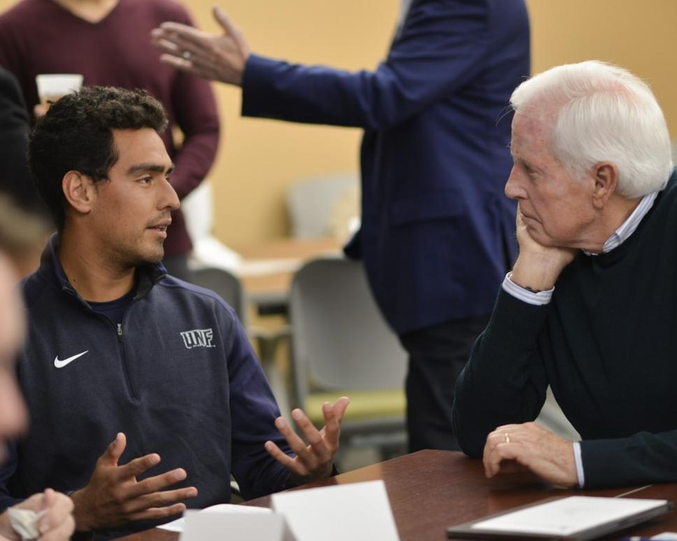 UNF student sitting at a table talking to their career mentor at the TLI Mentor Orientation event