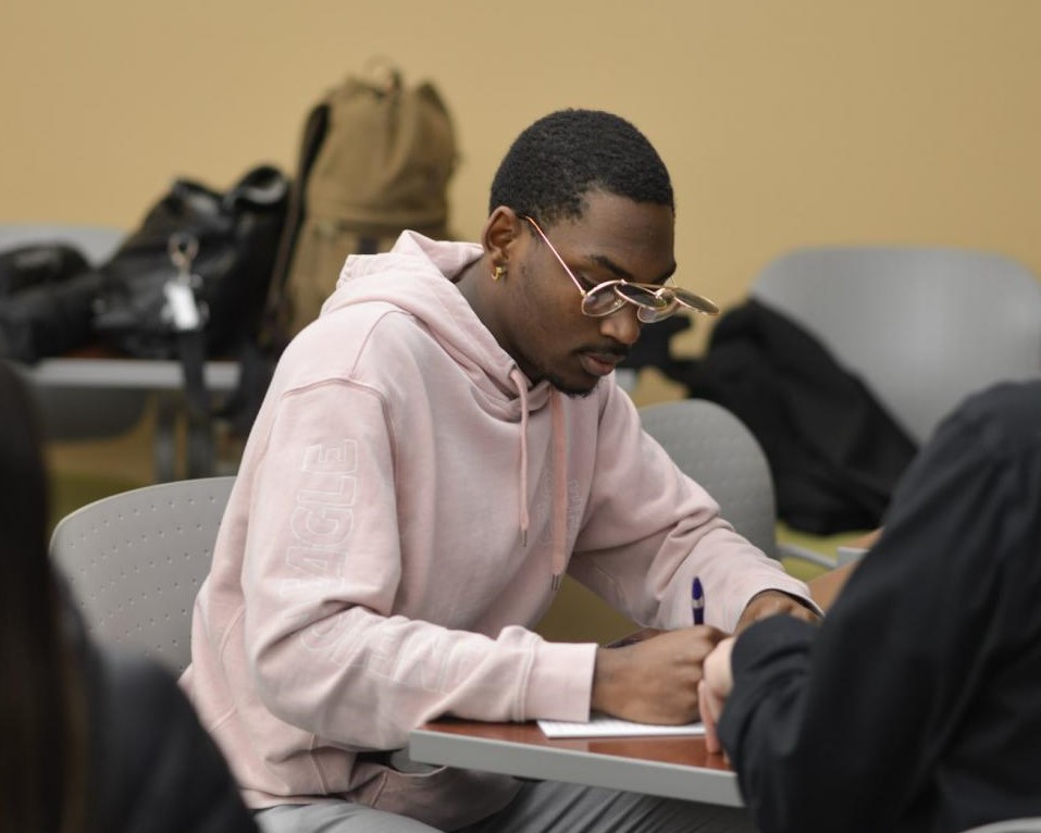 Male students sitting at a table completing work on paper