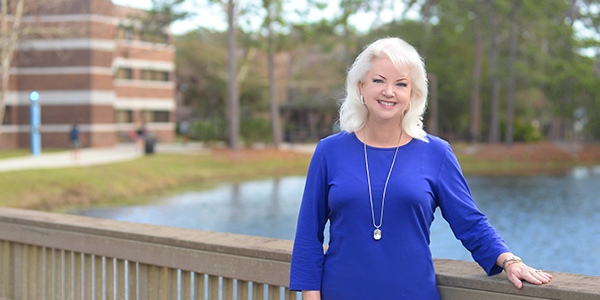 Alumna Debbie Johnson posing in front of a lake at UNF