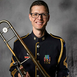 Headshot of Luke Brimhall in army uniform holding a trombone