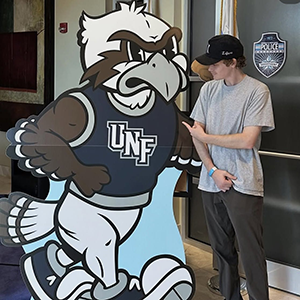 Photo of Will Pease standing next to UNF osprey mascot cutout