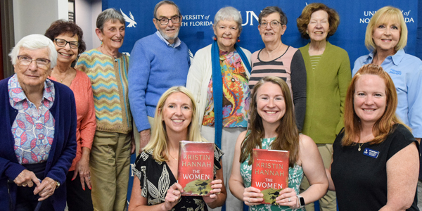 UNF alumni holding up book club books