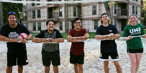UNF alumni standing behind a volleyball net