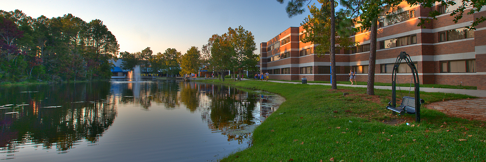 students walking along pond outside a residence hall
