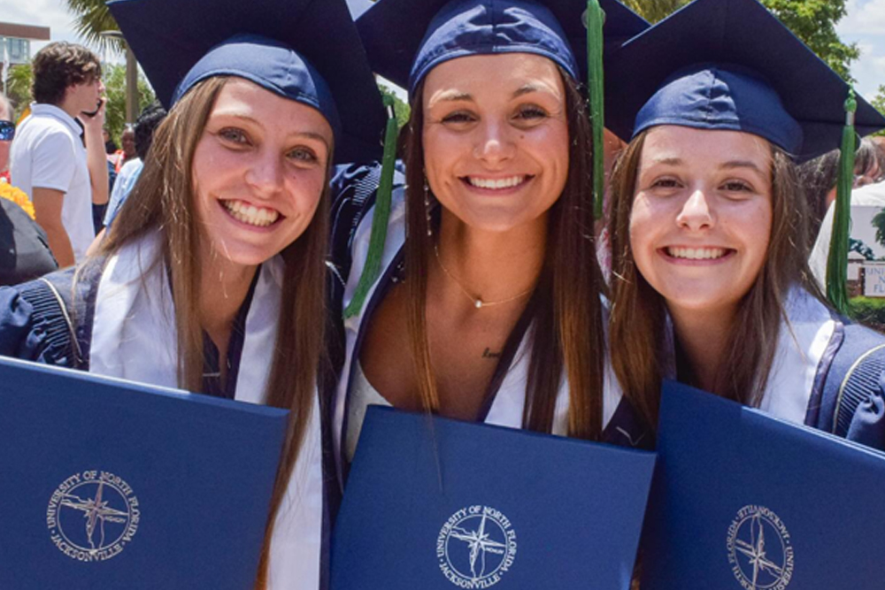 3 graduates with their degrees